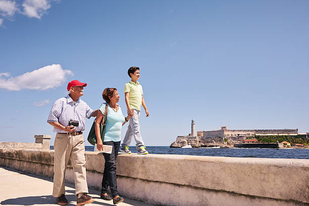 Grandparents Grandson Family On Holidays In Havana Cuba Happy tourists on holidays in Havana, Cuba. Hispanic family with grandpa, grandma and grandson traveling and walking together on the Malecon morro castle havana stock pictures, royalty-free photos & images