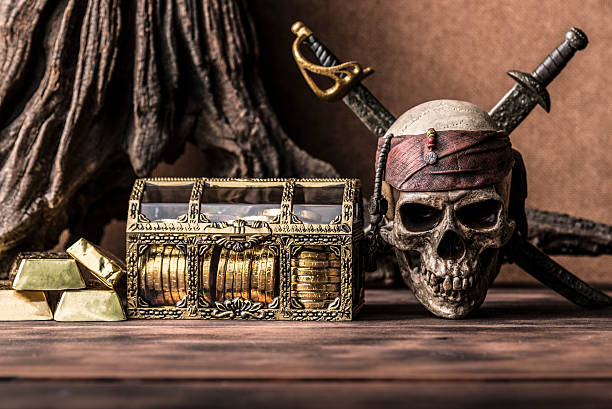still life photography with pirate skull holding two swords and treasure coffer, gold bar,  bullion. Halloween concept