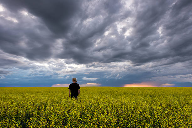 istock Lone guy standing in wide open farm field during storm 547436246