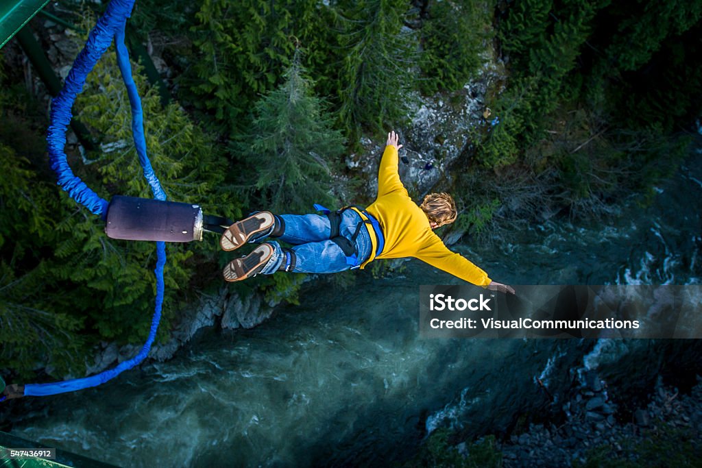 Bungee jumping. Young man bungee jumping over river. Bungee Jumping Stock Photo