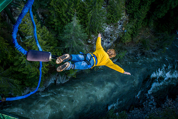 Bungee jumping. Young man bungee jumping over river. exhilaration photos stock pictures, royalty-free photos & images