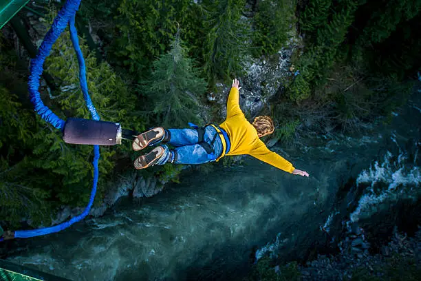 Young man bungee jumping over river.