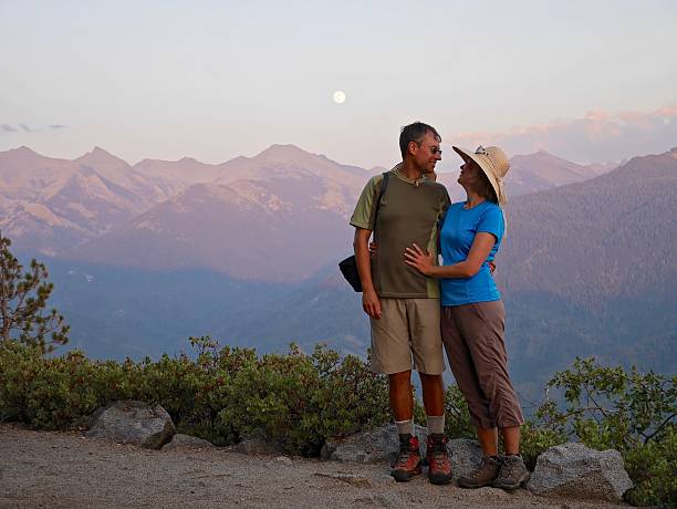Happy couple smiling and hugging by mountains.