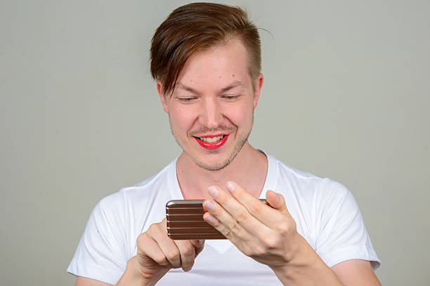 istock Happy man wearing make up and using phone 547441472