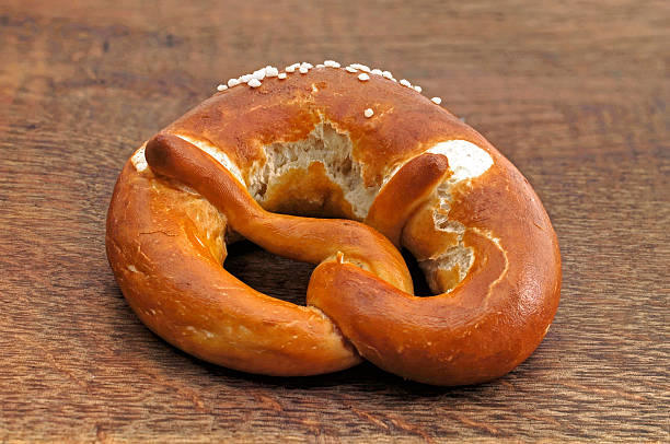 single fresh pretzel on a wooden table - bretzl imagens e fotografias de stock