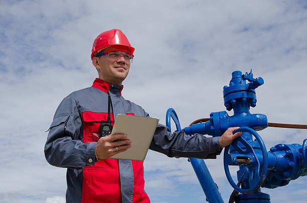 pracownik w pobliżu zaworu głowicy studni - oil industry digital tablet manual worker mining zdjęcia i obrazy z banku zdjęć