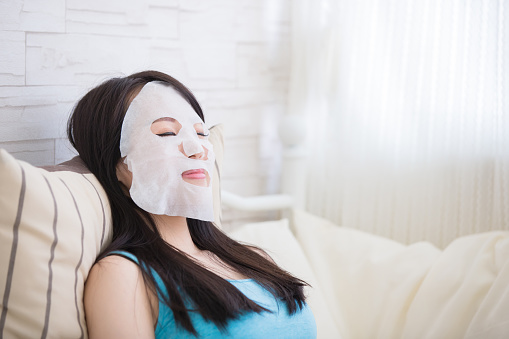relax young woman with  facial mask  in living room at home