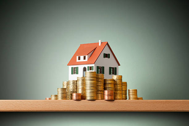 House on money stack Miniature model house standing on a stack of coins. real estate stock pictures, royalty-free photos & images