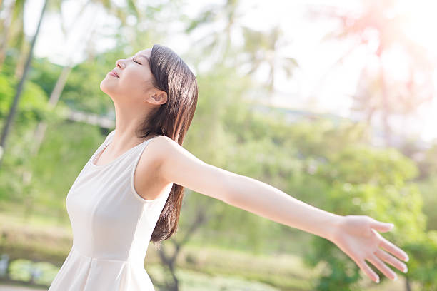 young woman raising her arms young woman raising her arms and smile to you, nature green background women healthy lifestyle beauty nature stock pictures, royalty-free photos & images