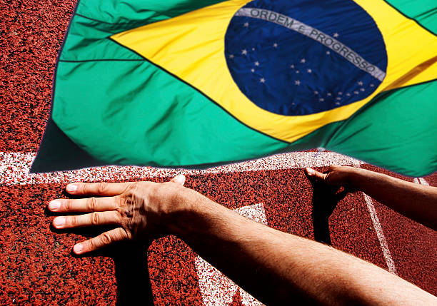 istock Hands on starting line - running track and Brazil flag 547494742