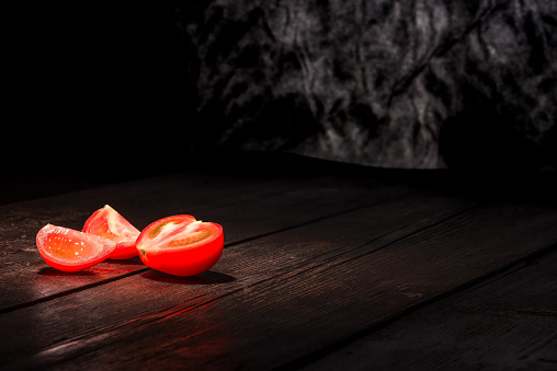Red tomato on the dark wooden surface.