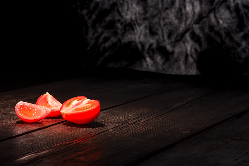 Red tomato on the dark wooden surface.