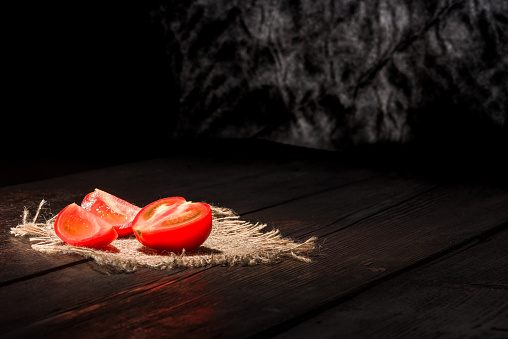 Red tomato on the dark wooden surface.