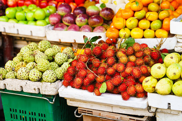 Asian farmer market selling Passion fruit and cherimoya and other Asian street farmer market selling fresh fruit and berry in Hoi An, Vietnam. Passion fruit, litchi, cherimoya, mango and other. Red, orange and green colors. annona reticulata stock pictures, royalty-free photos & images