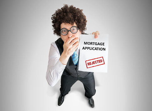 Disappointed man is showing document with denied mortgage application.