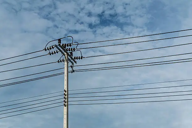 Photo of Electric pole and electricity line with against blue cloudy sky,