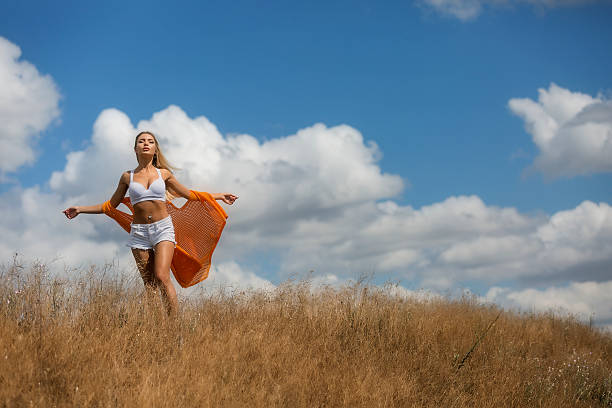 Summer freedom. Young attractive woman in sport clothing standing on top of hill