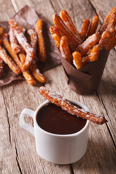 cocina española: churos y chocolate caliente en la mesa. vertical - churro chocolate cup sweet food fotografías e imágenes de stock