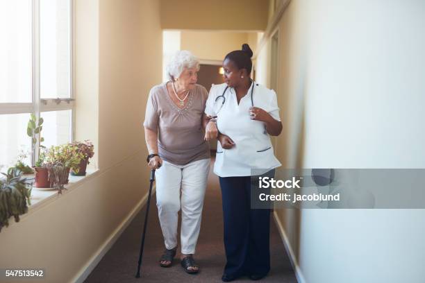 Senior Woman With Walking Stick Being Helped Stock Photo - Download Image Now - Nursing Home, Walking, Walking Cane