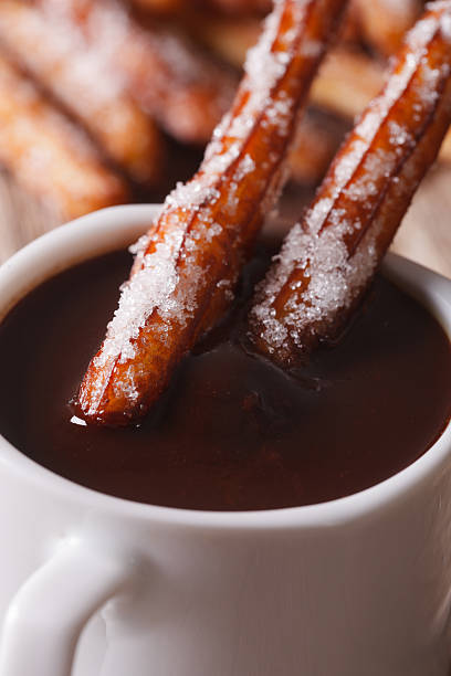 istock Traditional churros dipped in a cup of chocolate macro. vertical 547514124
