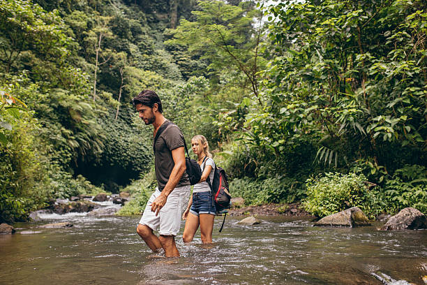 istock Couple crossing mountain stream 547516228
