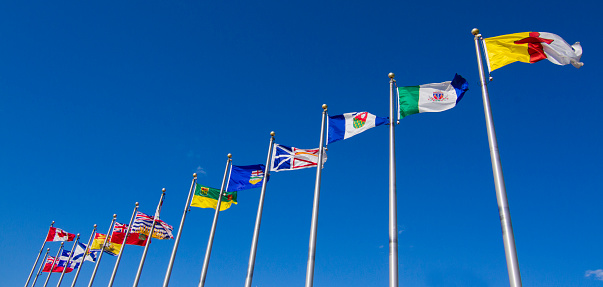Canadian provinces and territory flags on blue sky in Ottawa