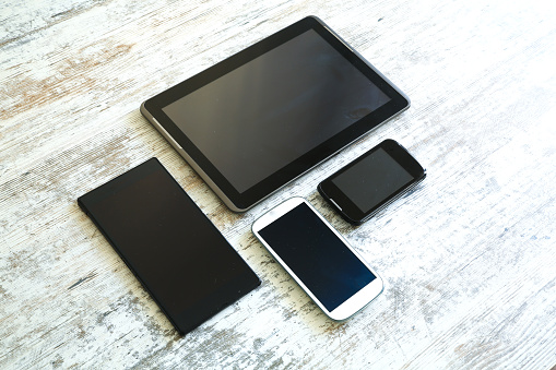 Various smartphones and Tablet Pcs on a wooden Table.