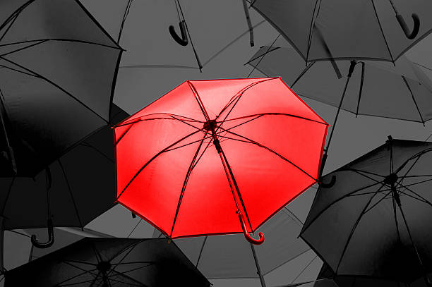 istock Red umbrella in black and white umbrellas 547528022