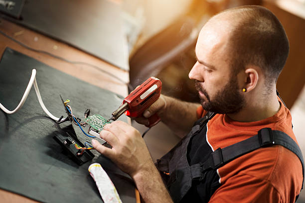 istock Repairman working in workshop and soldering electric board 547530028