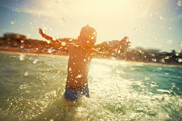 istock Little boy having fun playing and splashing in sea waves 547530098