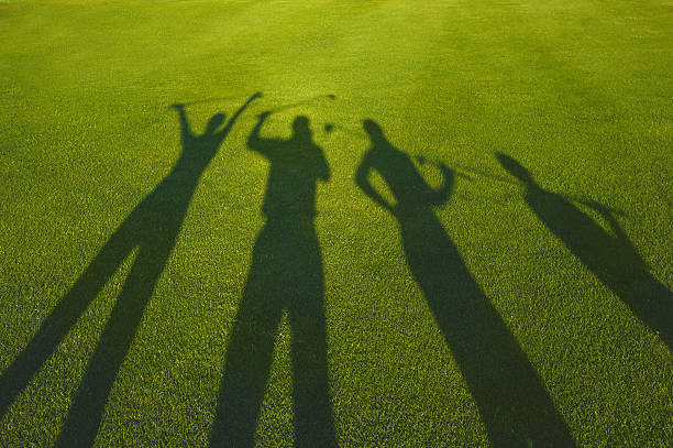 Four golfers silhouette on grass stock photo
