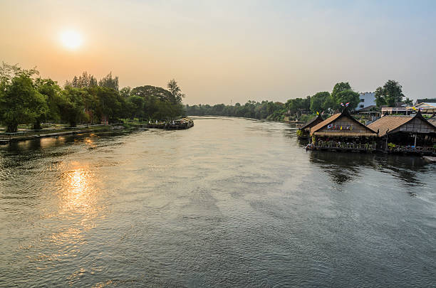 High angle view from bridge, beautiful landscape of Kwai Yai River at sunset and lifestyle of people on the waterfront in Kanchanaburi Province, Thailand
