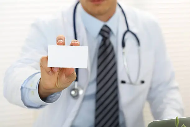 Photo of Male physician hand holding and giving white blank calling card