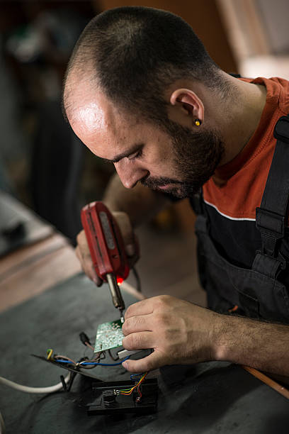 istock Repairman working in workshop and soldering electric board 547536802