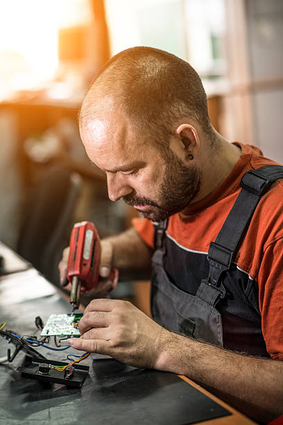 istock Repairman working in workshop and soldering electric board 547536944