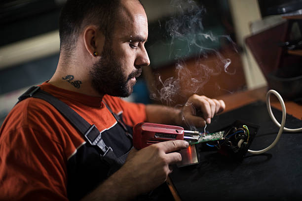 istock Repairman working in workshop and soldering electric board 547537260