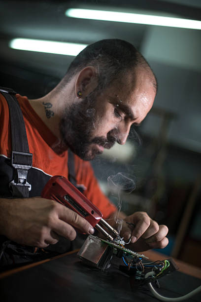 istock Repairman working in workshop and soldering electric board 547537380