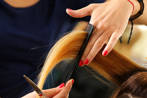 Peluquería femenina sostiene en el mechón de la mano del pelo rubio photo