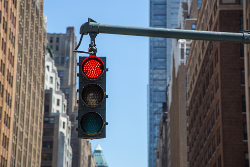 yellow traffic light on the background of skyscrapers in New York. Glowing red light.