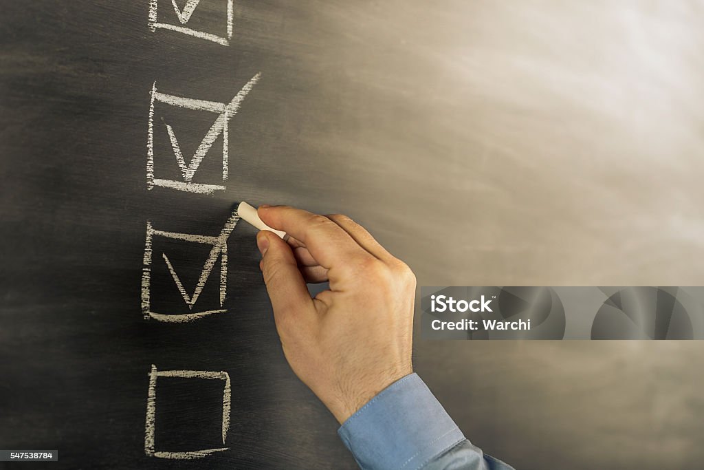 filling a checklist businessman filling a checklist on blackboard Check Mark Stock Photo