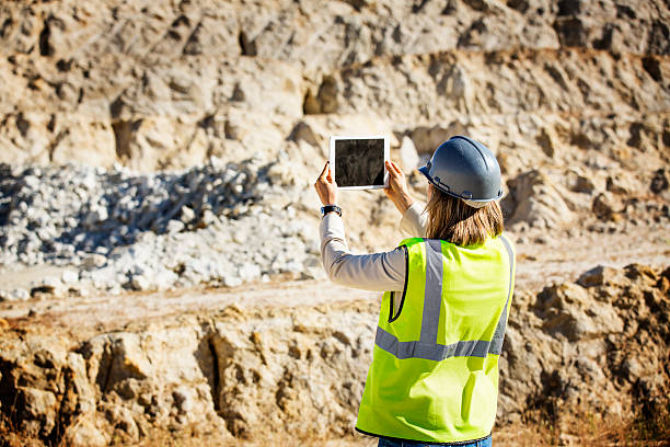 Female architect photographing quarry Rear view of female architect in protective workwear photographing quarry through digital tablet mining stock pictures, royalty-free photos & images