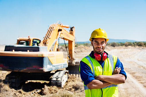 Portrait of confident quarry worker standing arms crossed at construction site