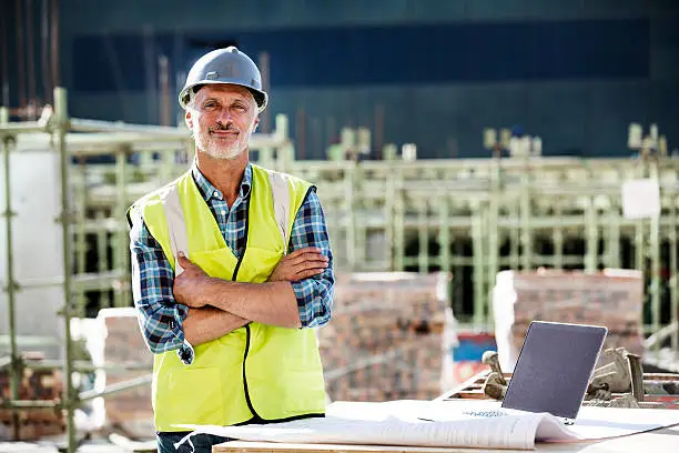 Portrait of confident male architect standing arms crossed at construction site