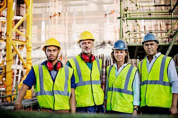 Portrait of confident architects and workers standing together at construction site