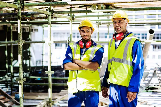 Portrait of confident construction workers in protective workwear standing at site