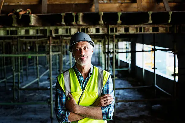 Portrait of confident male architect standing arms crossed at construction site