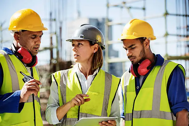 Male and female architects discussing while using digital tablet at construction site