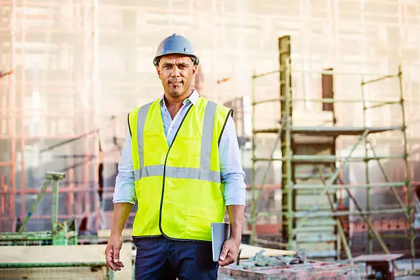 Portrait of confident male architect holding digital tablet at construction site