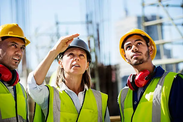 Female architect explaining plan to male colleagues at construction site