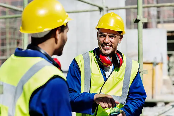 Happy construction worker talking to colleague at site
